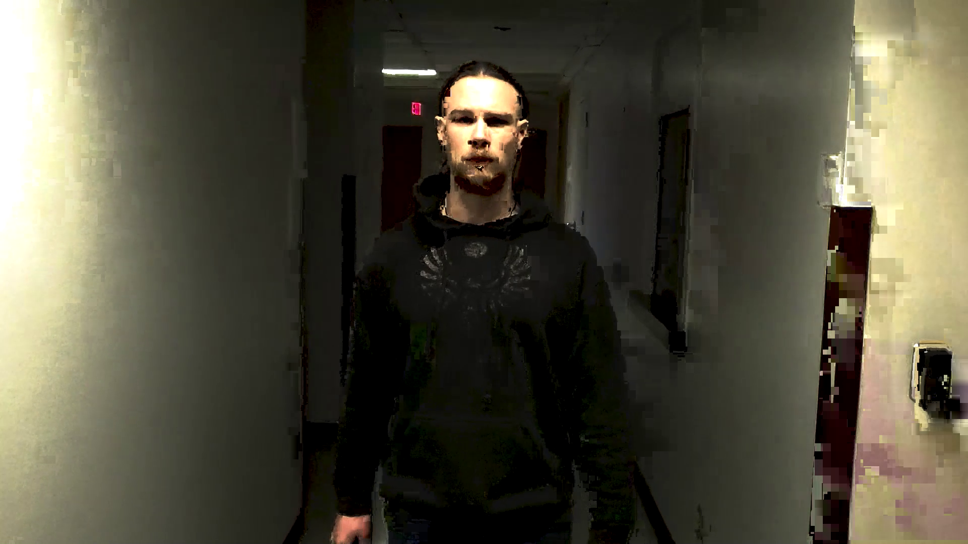 Production still from short film Outside. Reggie stands in a dark industrial hallway with his cane. He is framed perfectly in the center, the only light shining brightly on his face from above