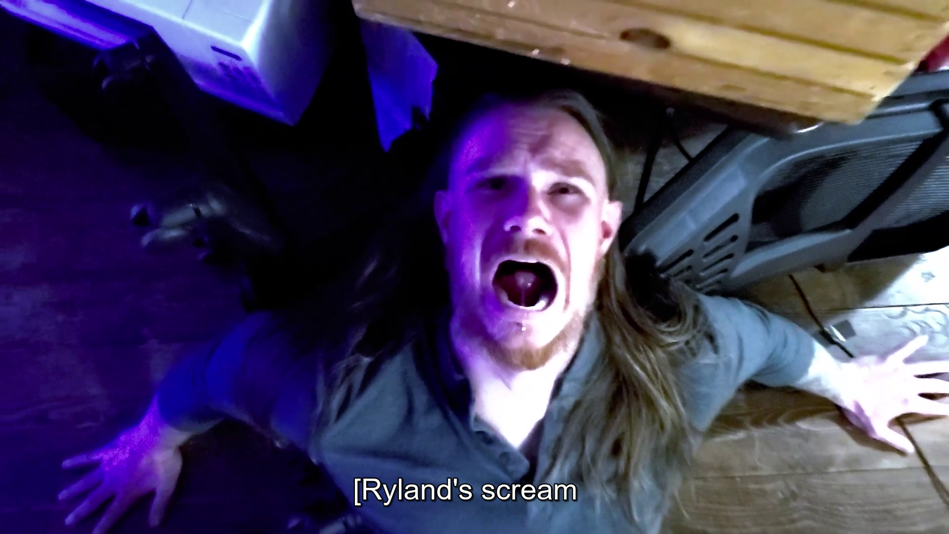 Production still from short film Outside. Reggie is screaming up at the ceiling in terror, his back and arms bracing against a barricaded front door.